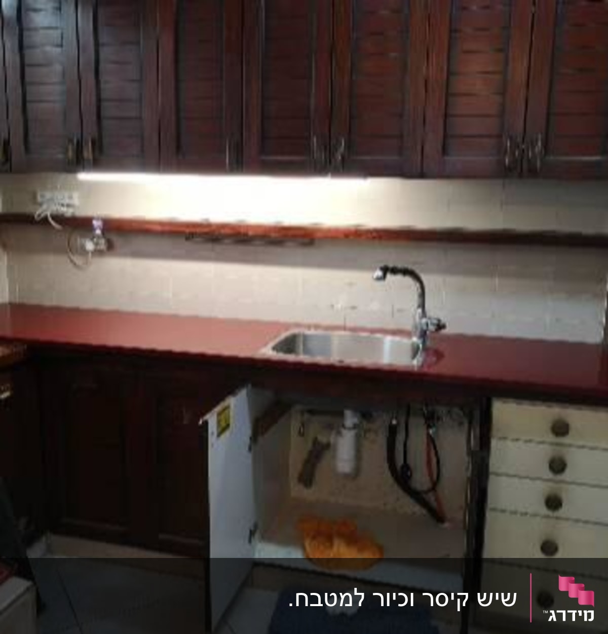 מטבח עם משטח עבודה כהה וכיור נירוסטה